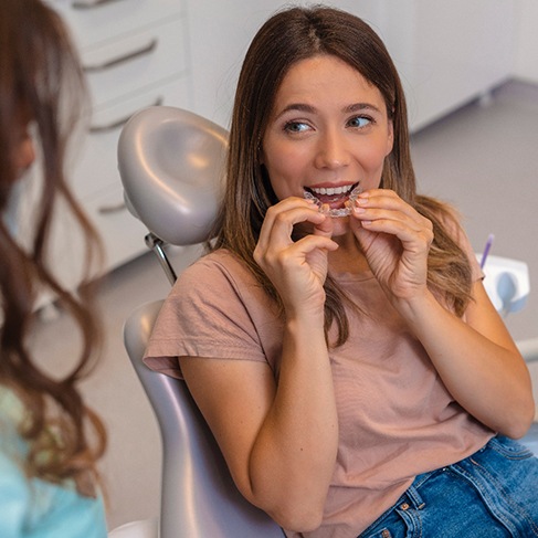 Smiling patient putting on clear aligner