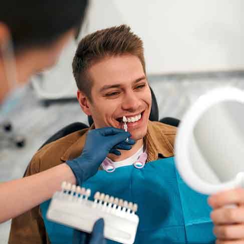 Smiling patient looking at shade of veneer in reflection